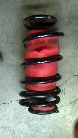 Picture of an automotive air bag inside a coil spring. Air bag has blowout hole.